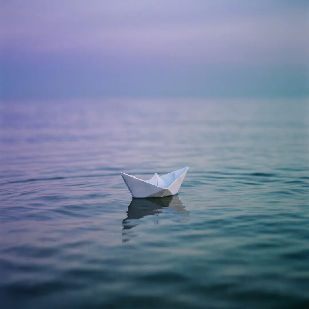 A white paper boat afloat on calm water